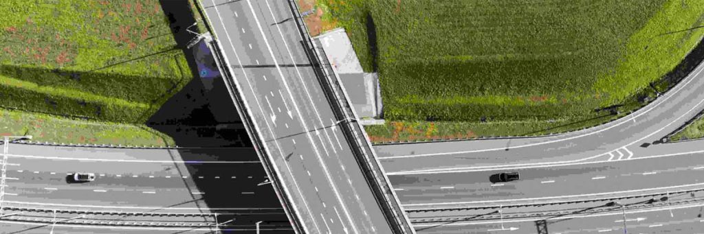 تصویر هوایی از یک پل زیرگذر جاده ای در کنار زمین چمن سبز رنگ با کمک کوادکوپتر